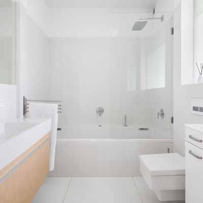 White walled bathroom with shower with a glass door and a brown cabinet sink